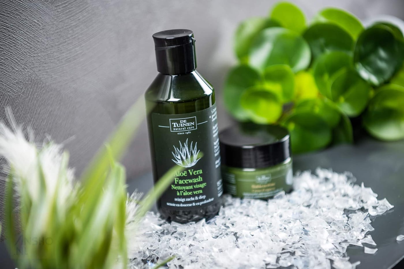 Green PET bottle and jar with facial care products on a bed of recycled PET flakes